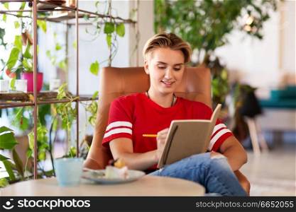 people, leisure and inspiration concept - happy woman or teenage girl with notebook at coffee shop or cafe. teenage girl with notebook at coffee shop or cafe