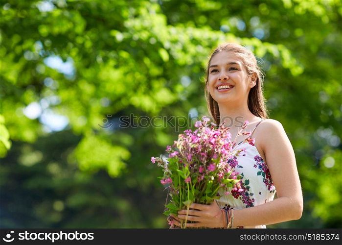 people, leisure and lifestyle concept - happy smiling young woman with flowers in summer park. happy young woman with flowers in summer park