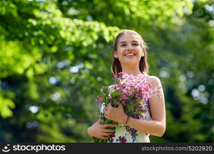 people, leisure and lifestyle concept - happy smiling young woman with flowers in summer park. happy young woman with flowers in summer park