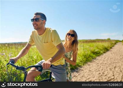 people, leisure and lifestyle concept - happy young couple riding bicycle together in summer. happy couple riding bicycle together in summer