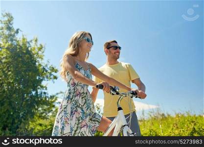 people, leisure and lifestyle concept - happy young couple with bicycle at country. happy couple with bicycle at country