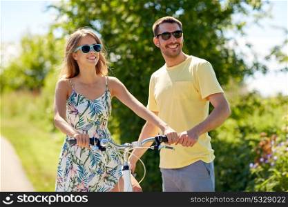 people, leisure and lifestyle concept - happy young couple with bicycle at country. happy couple with bicycle at country