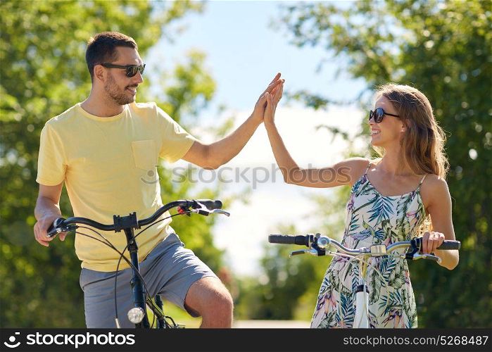 people, leisure and lifestyle concept - happy young couple with bicycles at country making high five. happy couple with bicycles making high five