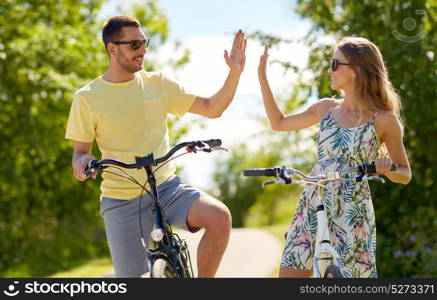 people, leisure and lifestyle concept - happy young couple with bicycles at country making high five. happy couple with bicycles making high five