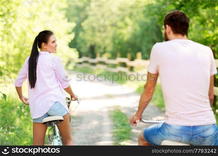 people, leisure and lifestyle concept - happy young couple with bicycles at summer park. happy couple with bicycles at summer park