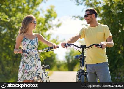 people, leisure and lifestyle concept - happy young couple with bicycles on country road. happy couple with bicycles on country road