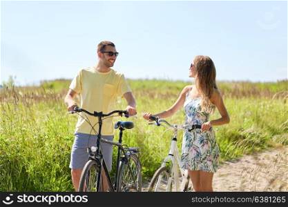 people, leisure and lifestyle concept - happy young couple with bicycles on country road. happy couple with bicycles on country road