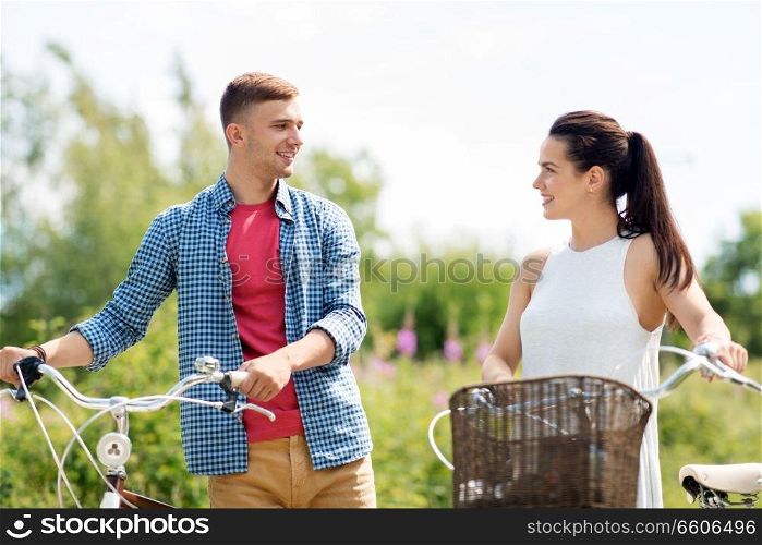 people, leisure and lifestyle concept - happy young couple with fixed gear bicycles in summer. happy couple with fixed gear bicycles in summer