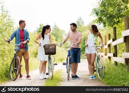 people, leisure and lifestyle concept - happy young friends with fixed gear bicycles on country road in summer. happy friends with fixed gear bicycles in summer