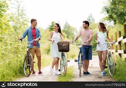 people, leisure and lifestyle concept - happy young friends with fixed gear bicycles on country road in summer. happy friends with fixed gear bicycles in summer