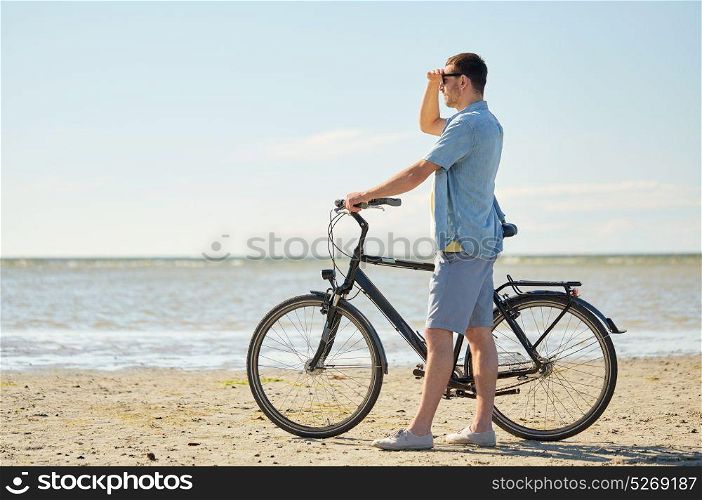 people, leisure and lifestyle concept - happy young man with bicycle on beach . happy young man with bicycle on beach