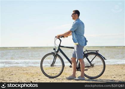 people, leisure and lifestyle concept - happy young man with bicycle on beach . happy young man with bicycle on beach