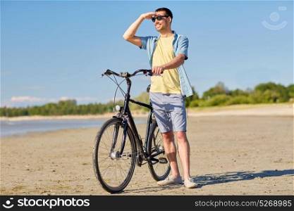 people, leisure and lifestyle concept - happy young man with bicycle on summer beach. happy man with bicycle on summer beach