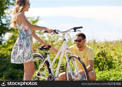people, leisure and lifestyle concept - young couple fixing bicycle on country road. young couple fixing bicycle on country road