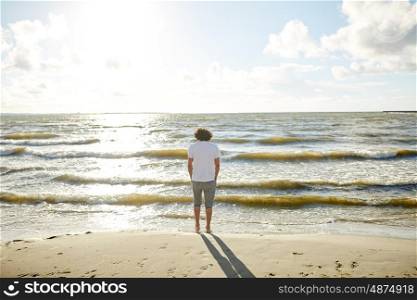 people, leisure and nature concept - young man at sea summer beach