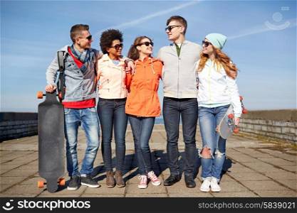 people, leisure and sport concept - group of happy teenage friends with longboards talking on city street