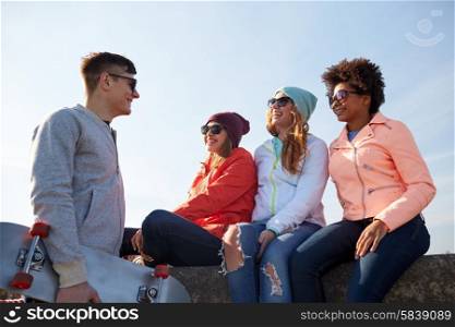 people, leisure and sport concept - group of happy teenage friends with skateboard talking on city street