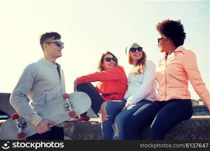 people, leisure and sport concept - group of happy teenage friends with longboard talking on city street