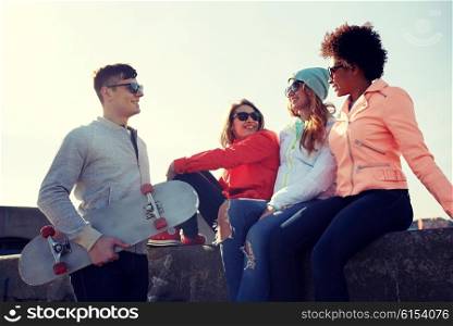 people, leisure and sport concept - group of happy teenage friends with skateboard talking on city street