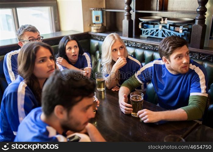 people, leisure and sport concept - worried friends or football fans drinking beer and watching soccer game or match at bar or pub