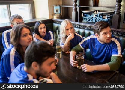people, leisure and sport concept - worried friends or football fans drinking beer and watching soccer game or match at bar or pub