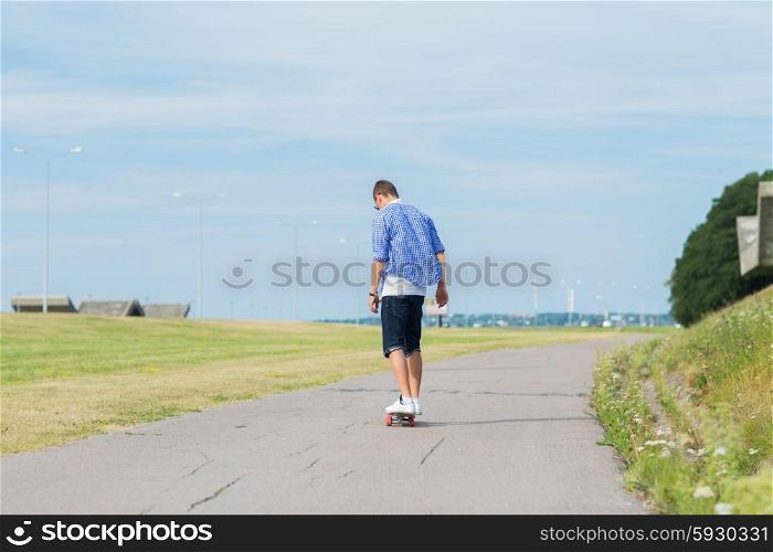 people, leisure and sport concept - young man riding on longboard or skateboard on road outdoors