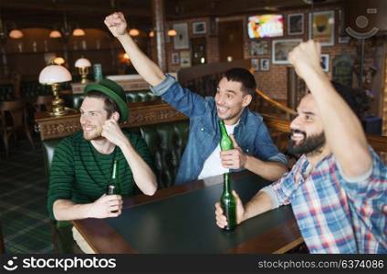 people, leisure and st patricks day concept - happy male friends drinking bottled beer and and celebrating at bar or pub. happy male friends drinking beer at bar or pub