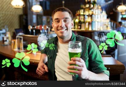people, leisure and st patricks day concept - happy young man drinking green beer at bar or pub. man drinking green beer at bar or pub