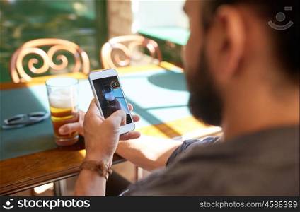 people, leisure and technology concept - close up of man with smartphone photographing beer at bar or pub
