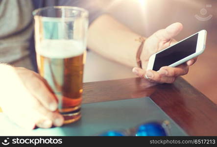 people, leisure and technology concept - close up of man with smartphone drinking beer and reading message at bar or pub. close up of man with smartphone and beer at pub. close up of man with smartphone and beer at pub