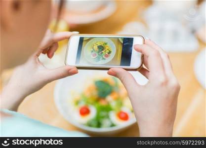 people, leisure and technology concept - close up of woman hands with smartphone taking picture of food at restaurant
