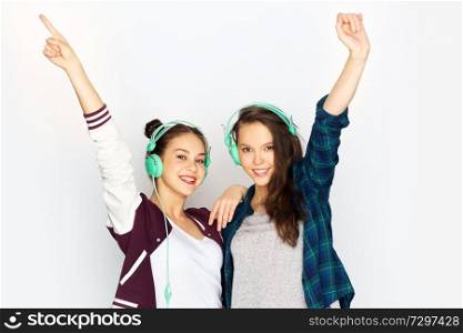 people, leisure and technology concept - smiling teenage girls in earphones listening to music and having fun over white background. teenage girls in earphones listening to music