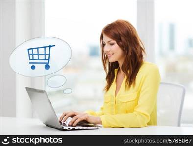 people, leisure and technology concept - smiling young woman with laptop computer and trolley icon shopping online at home