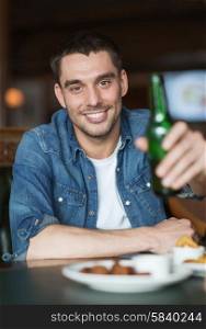 people, leisure, celebration and bachelor party concept - happy young man drinking beer at bar or pub