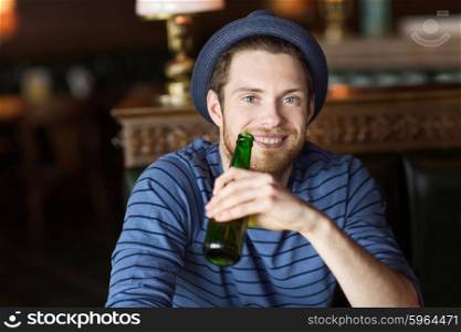 people, leisure, celebration and bachelor party concept - happy young man drinking beer at bar or pub