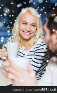 people, leisure, communication and season concept - happy couple meeting and drinking tea or coffee at winter cafe
