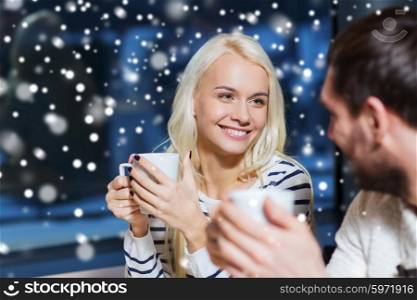 people, leisure, communication and season concept - happy couple meeting and drinking tea or coffee at winter cafe