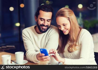 people, leisure, communication, eating and drinking concept - happy couple with smartphone drinking tea or coffee at cafe