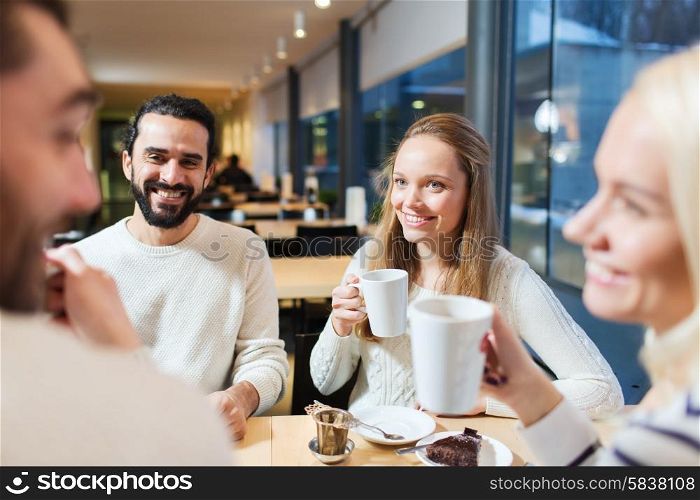 people, leisure, communication, eating and drinking concept - happy friends meeting and drinking tea or coffee at cafe