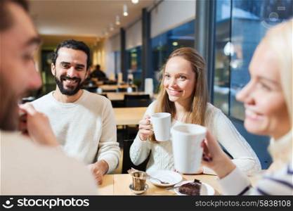 people, leisure, communication, eating and drinking concept - happy friends meeting and drinking tea or coffee at cafe