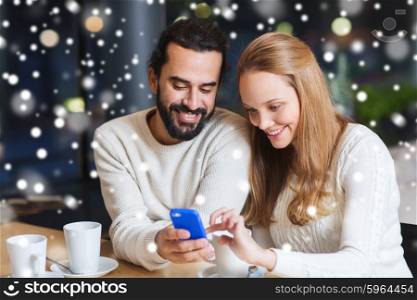 people, leisure, communication, technology and season concept - happy couple with smartphone drinking tea or coffee at winter cafe