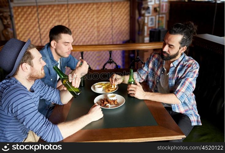 people, leisure, friendship and bachelor party concept - happy male friends drinking bottled beer and eating snacks at bar or pub