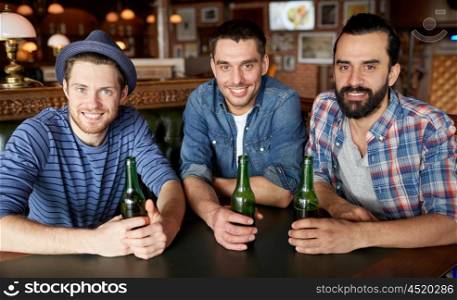 people, leisure, friendship and bachelor party concept - happy male friends drinking bottled beer at bar or pub