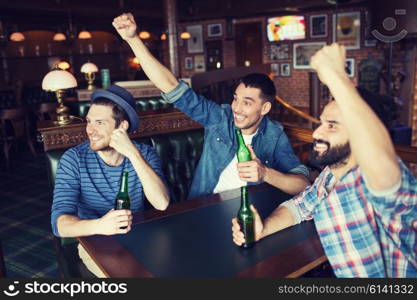 people, leisure, friendship and bachelor party concept - happy male friends drinking bottled beer and raised hands rooting for football match at bar or pub