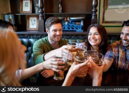 people, leisure, friendship and celebration concept - happy friends drinking draft beer and clinking glasses at bar or pub