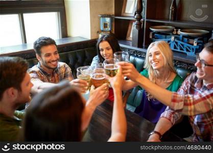 people, leisure, friendship and celebration concept - happy friends drinking draft beer and clinking glasses at bar or pub