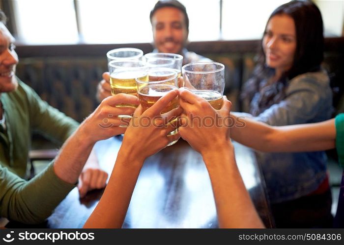 people, leisure, friendship and celebration concept - happy friends drinking draft beer and clinking glasses at bar or pub. happy friends drinking beer at bar or pub. happy friends drinking beer at bar or pub