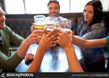 people, leisure, friendship and celebration concept - happy friends drinking draft beer and clinking glasses at bar or pub. happy friends drinking beer at bar or pub. happy friends drinking beer at bar or pub