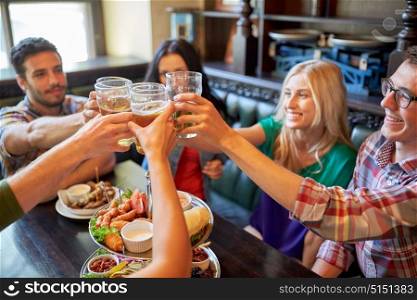 people, leisure, friendship and celebration concept - happy friends drinking draft beer and clinking glasses at bar or pub. happy friends drinking beer at bar or pub