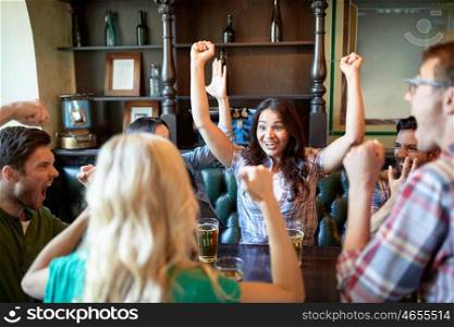 people, leisure, friendship and celebration concept - happy friends with beer celebrating victory at bar or pub